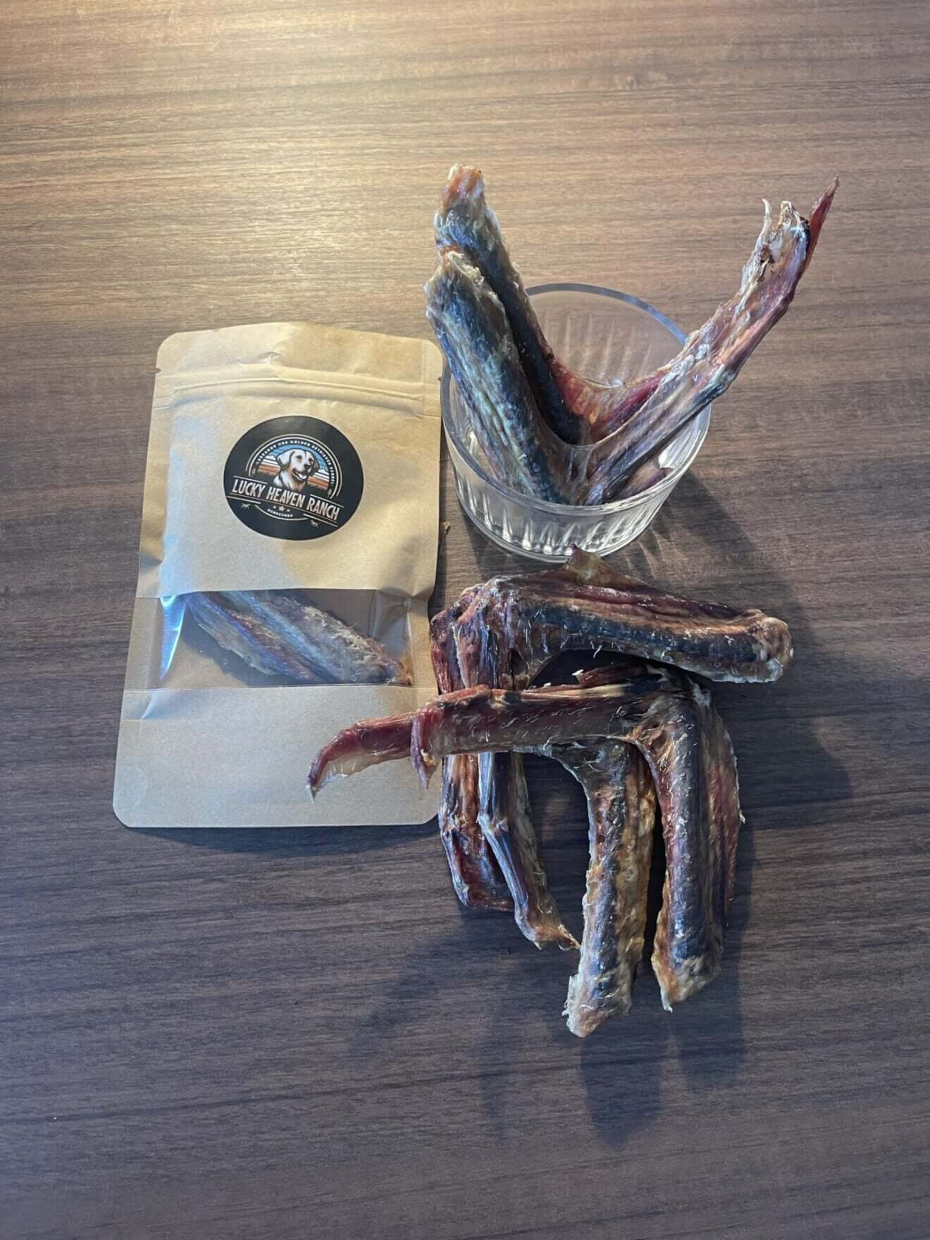 Entenflügel – Kauartikel für Hunde in einem Glas und einer Verpackung auf einem Holzuntergrund.