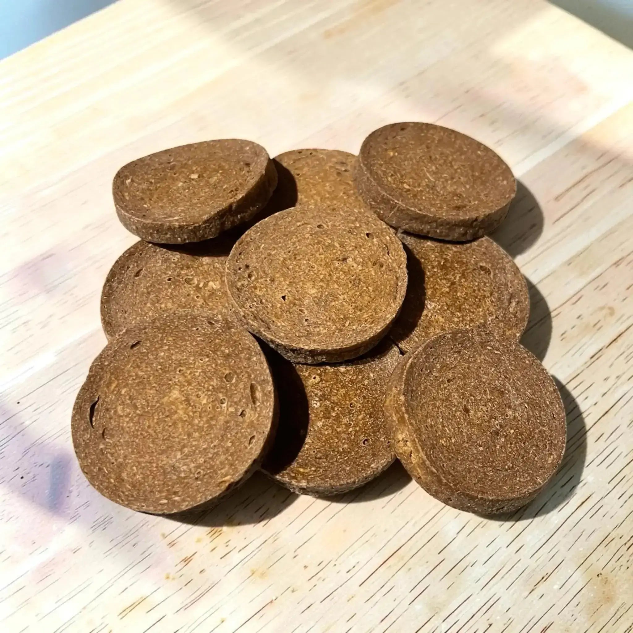 Hirsch Knusperscheiben – Kausnack für Hunde in runder Form auf Holzuntergrund